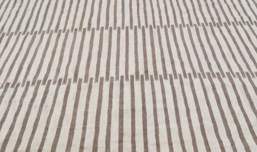 Close-up detail of a flat weave on a beige and brown striped Moroccan kilim rug.