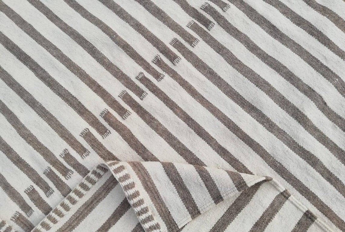 Close-up detail of a textured surface on a beige and brown striped Moroccan kilim rug.