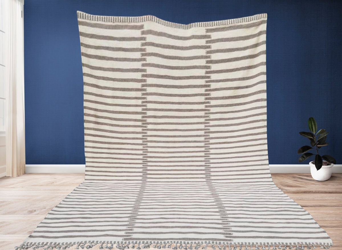 Lifestyle shot of a beige and brown striped Moroccan kilim rug on a natural background.