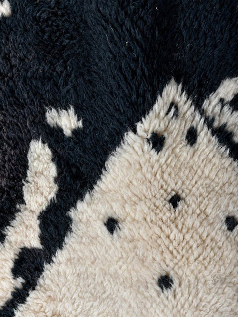 Close-up detail of the corner of the zebra print rug showing woven edge and diamond pattern.