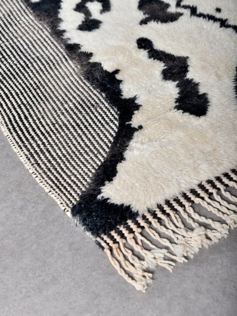 Close-up detail of the zebra print rug with woven texture and fringe edges.
